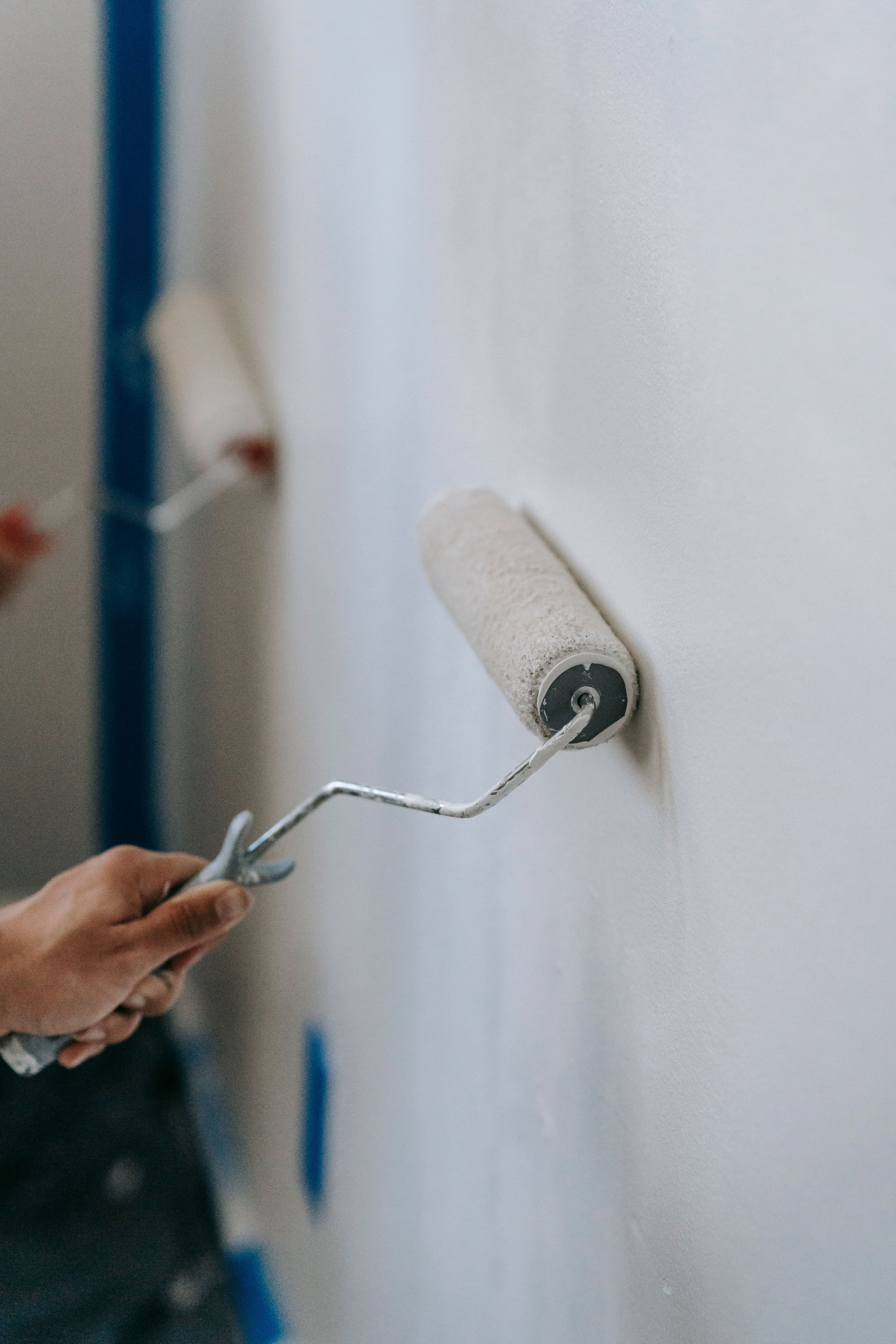 Professional house painter rolling fresh paint on a home exterior