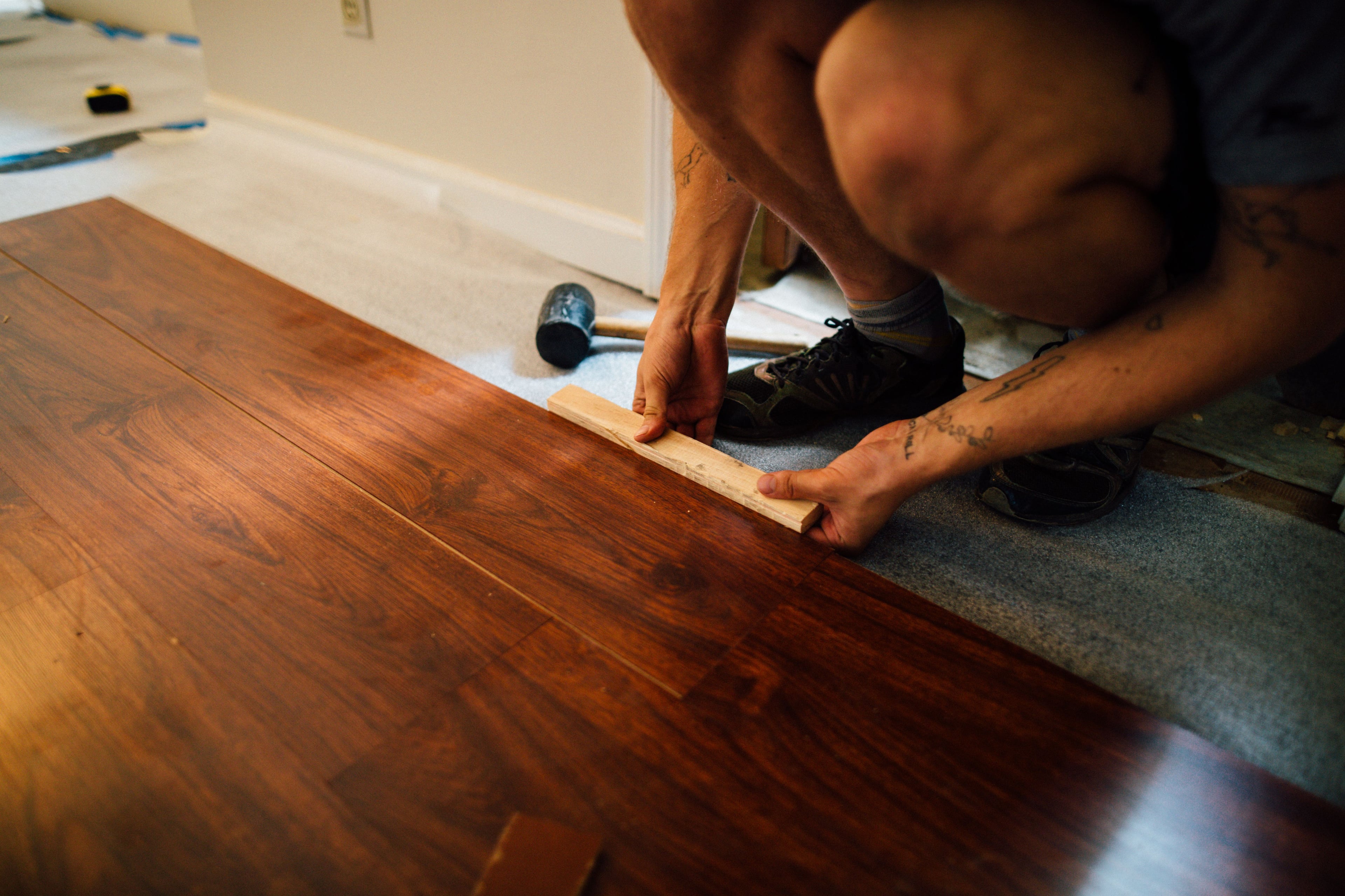 Professional flooring installer laying hardwood plank flooring during a home renovation